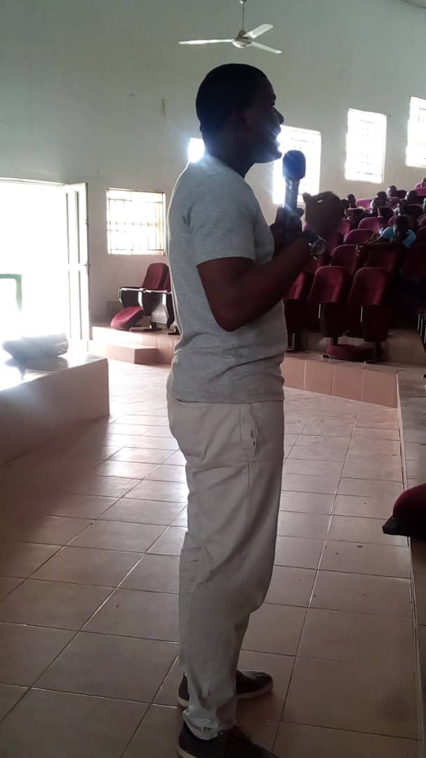 Adebayo Chike speaking into a microphone in an auditorium