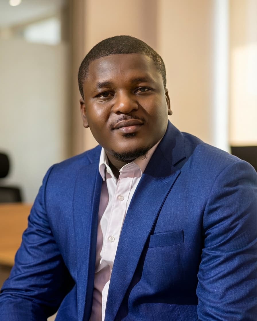Adebayo Chike, seated in an office, wearing a blue suit