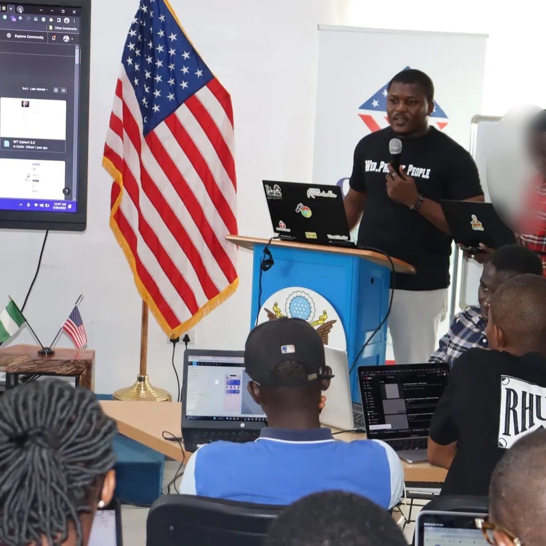 Adebayo Chike at the podium at American Corner Ikeja, one attendee blurred for privacy
